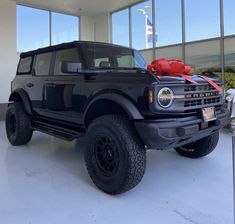 a black truck with a red bow on it's hood