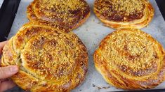 there are four breads that have been baked on the baking sheet and being held by someone's hand