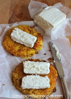 some food is sitting on top of wax paper and next to a knife with butter