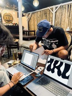 three people sitting at a table with laptops