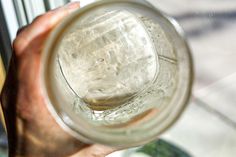 a person holding a glass jar with water in it