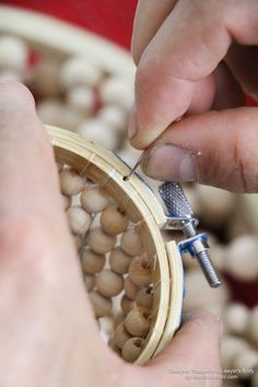 a person is working on some beads with a small metal object in front of them