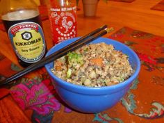 a blue bowl filled with rice and vegetables next to chopsticks on a table