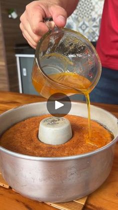 a person pouring something into a pan on top of a wooden table