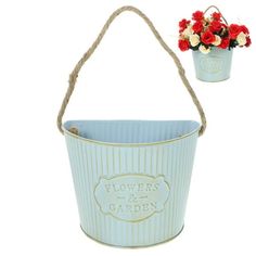 a blue bucket with flowers in it and a rope handle hanging from the side, on a white background