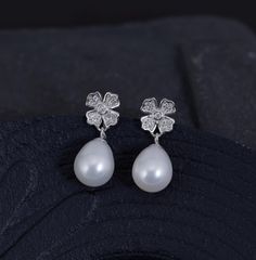 Material               :  Genuine Natural White Freshwater Pearl with Cubic Zirconia Flower in 925 Sterling Silver Post Quantity              :  One Pair earring Pearl Color          :  Natural White Freshwater Pearl Shape                  :   Oval / Rice Pearls with high luster Bead Size            :  8 x 10mm approx. Earring Length   :  2 cm / 0.75 inch approx. (including the pearl) *Due to the pearls are naturally grown, they won't be identical to each other* Lead Time & Shipping :  We ship y Silver Bridal Earrings With Pearl Drop In Flower Shape, Sterling Silver Flower Pearl Drop Earrings, Silver Flower Shape Pearl Drop Earrings, Elegant White Nickel-free Pearl Earrings, Silver Pearl Drop Flower-shaped Earrings, Formal White Flower-shaped Pearl Earrings, White Pearl Flower-shaped Earrings, White Shell-shaped Pearl Drop Earrings, White Pearl Drop Shell-shaped Earrings