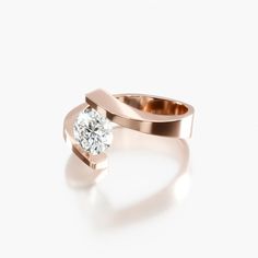 a rose gold ring with a single diamond in the center, on a white background