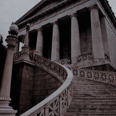 an old building with many pillars and steps leading up to the front door, on a cloudy day