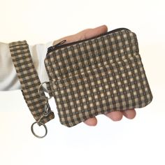 a hand holding a small purse with a keychain attached to the front pocket