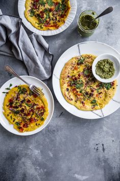 two white plates topped with omelets next to a bowl of salsa and a fork