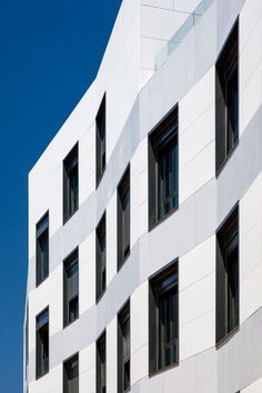 the building has many windows and is white with black shutters on each window sill