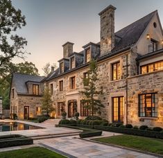 a large stone house with lots of windows and lights on it's front lawn