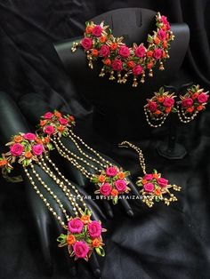 three pieces of jewelry with flowers and pearls on display in front of a black background