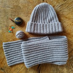 a knitted hat and mittens sitting on top of a wooden table next to buttons