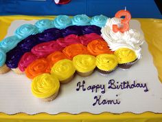 a birthday cake decorated with rainbow cupcakes and the number eight on it's side