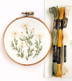 the embroidery kit is being displayed next to some thread and needle markers, including one with daisies on it