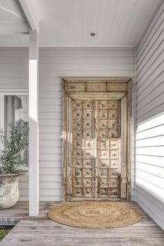 a door is open on the outside of a white house with a rug in front of it