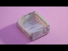 an origami money box sitting on top of a pink surface