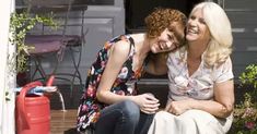 two women sitting next to each other on a porch