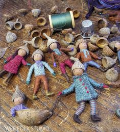 several knitted dolls are laying on the floor next to spools of thread