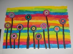 an art project is displayed on the wall in front of a whiteboard with colorful stripes and circles painted on it