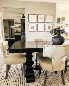 a dining room table with chairs and pictures on the wall in the backround