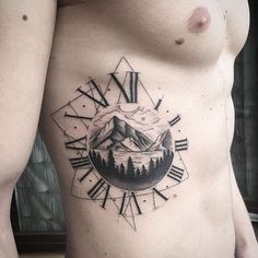 a man's chest with a clock and mountain scene tattoo on the left side