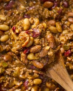 a wooden spoon filled with chili and nuts