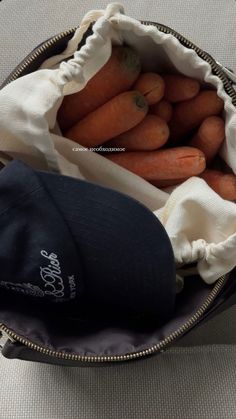 there is a bag full of carrots and a hat in the back pocket on the table