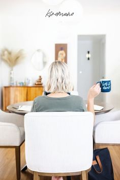 a woman sitting in a chair holding up a coffee mug