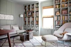 a living room filled with lots of bookshelves next to a couch and chair