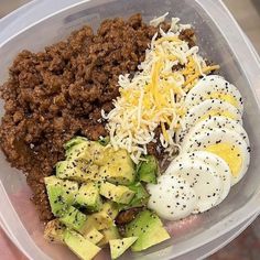 a plastic container filled with meat, eggs and other food items on top of it