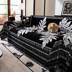 a black and white couch sitting in a living room next to a window with pictures on the wall