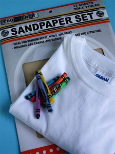 a t - shirt with crayons on it sitting next to a package of markers