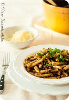 a white plate topped with pasta covered in sauce and parsley next to a yellow casserole dish