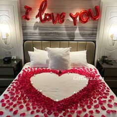 a bed with rose petals on it and the words i love you above it