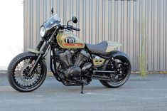 a gold motorcycle parked in front of a building with a metal fence and door behind it