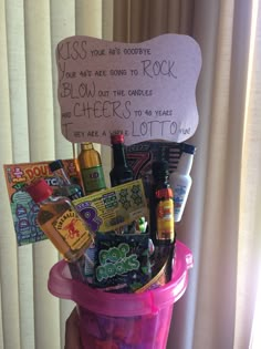 a pink bucket filled with lots of food and drinks next to a sign that says kiss your boozy you're going to rock blow out