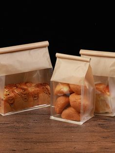 two clear plastic bags filled with bread on top of a wooden table