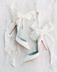 a pair of white high heels with bows on them