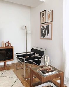 a living room filled with furniture next to a white wall and wooden floor covered in pictures