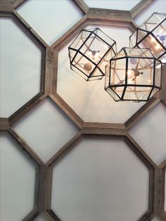 three lights hanging from the ceiling in a hexagonal room with white walls and glass panels