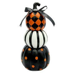 three black and white pumpkins stacked on top of each other with orange polka dots