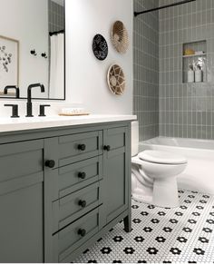 a white toilet sitting next to a bath tub under a bathroom mirror on top of a tiled floor