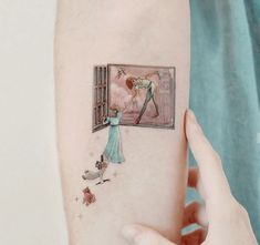 a person with a tattoo on their arm holding up a piece of paper that has an image of a man and woman looking out the window