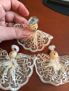 someone is holding three small angel figurines in their hand and they are sitting on lace doily