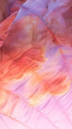 an abstract photograph of pink and orange feathers on a white umbrella with blue sky in the background