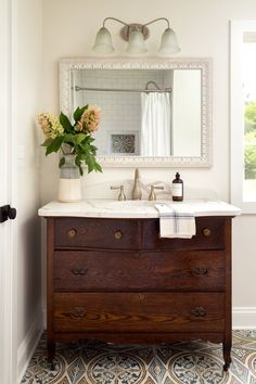 a bathroom with a sink, mirror and flowers on the counter in front of it