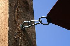 a chain is attached to the side of a wooden structure with a blue sky in the background