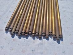 several brass tubes are lined up on a white tablecloth with tiny flowers in the background